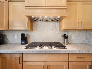 A kitchen with wooden cabinets, a gas stove, and a marble countertop. - Wasatch Lodge: Sleeps 16, Sauna/HotTub, Pool Table (Heber City)