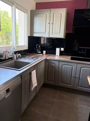 A kitchen with a dishwasher, sink, and cabinets.