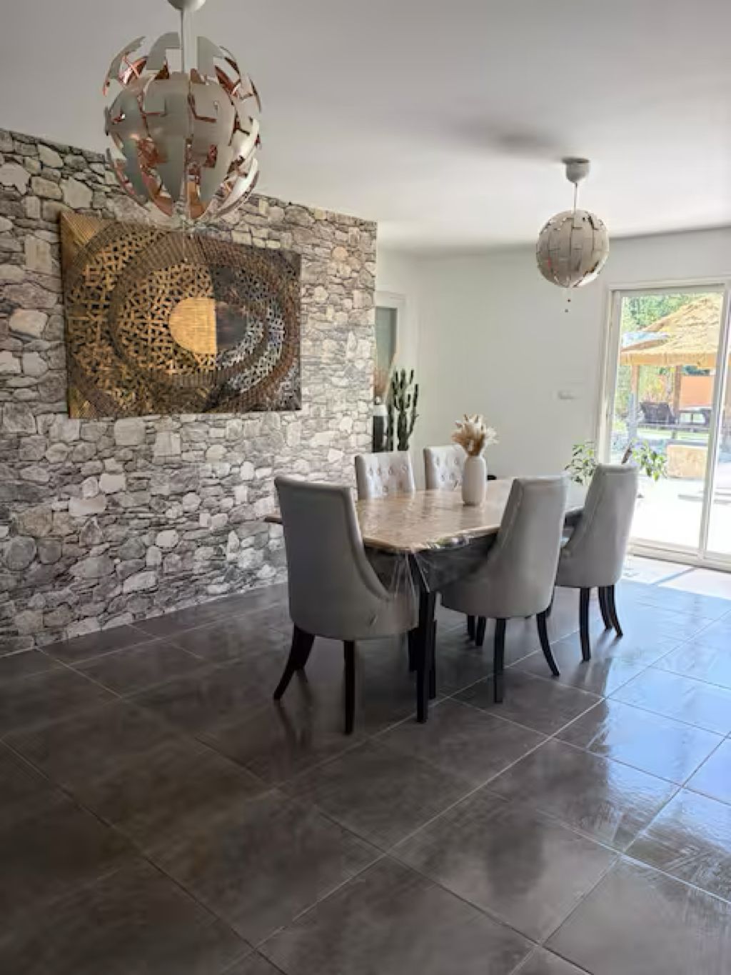 A dining area with a stone wall, a round table, and four chairs.