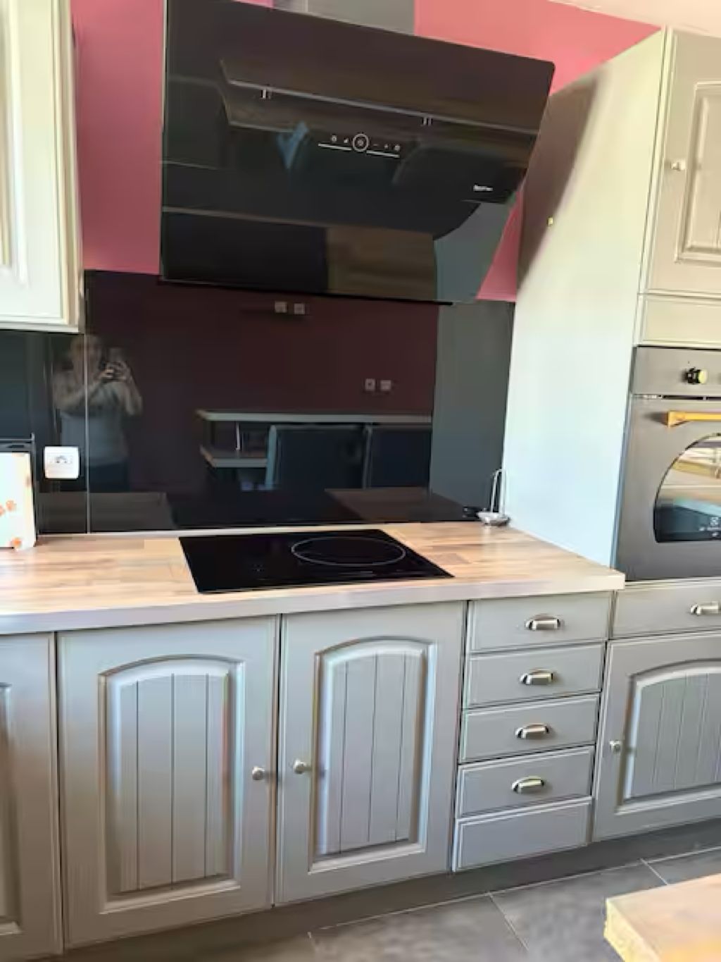 Een keuken met een zwarte afzuigkap, een ingebouwde oven en een RVS kookplaat.