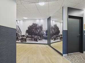 En hall med trägolv, en mörk dörr och en vägg prydd med ett historiskt fotografi.