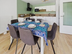 En matplats med ett bord dukat för fyra personer, omgivet av stolar.