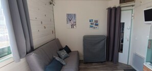 A small room with a sofa, a covered cabinet, and a door with a window. - Cozy studio apartment 50 meters from the base of the slopes (Arette la Pierre saint)