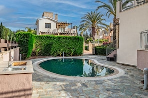 A swimming pool with a stone deck, surrounded by a hedge, and adjacent to a building with a balcony. - Spacious 5-bedroom house with AC in lovely Poli Chrysochous (Poli Chrysochous)
