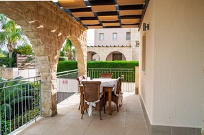 An outdoor patio with a stone archway, a table with chairs, and a building with arches in the background. - Spacious 5-bedroom house with AC in lovely Poli Chrysochous (Poli Chrysochous)