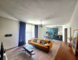 Ein Wohnzimmer mit einer Couch, einem Couchtisch und einer Küche im Hintergrund.