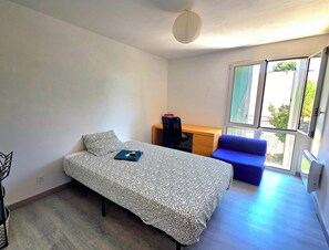 Ein Schlafzimmer mit einem Bett, einem Schreibtisch, einem Stuhl und einem Fenster.