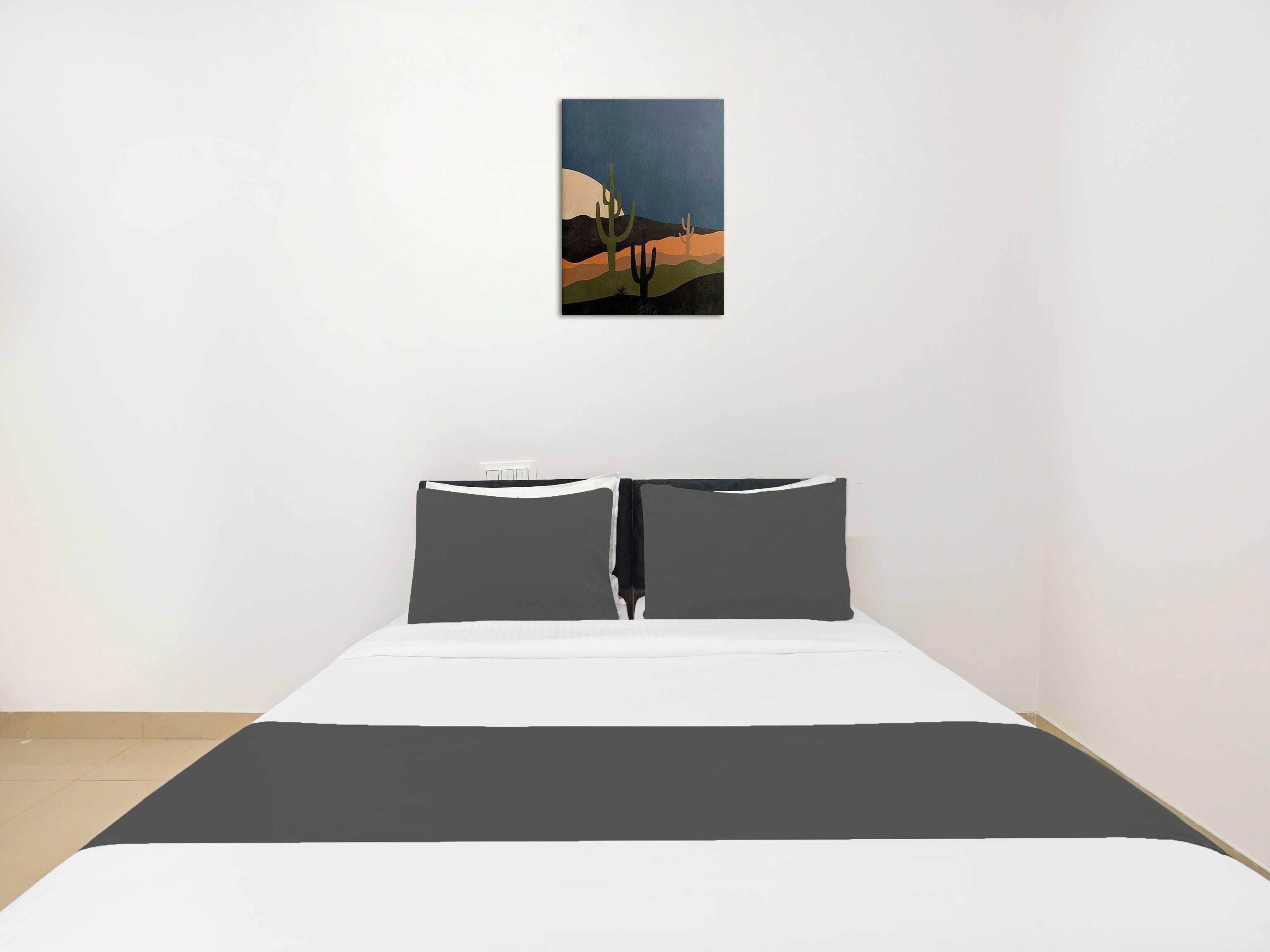 Un dormitorio con una cama, dos almohadas y un cuadro colgado en la pared.