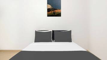 Un dormitorio con una cama, dos almohadas y un cuadro colgado en la pared.