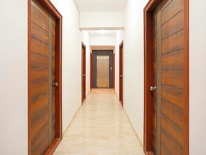 A corridor with wooden doors and a marble floor, leading to an elevator. - Collection O Karmelaram Railway Station (Bengaluru)