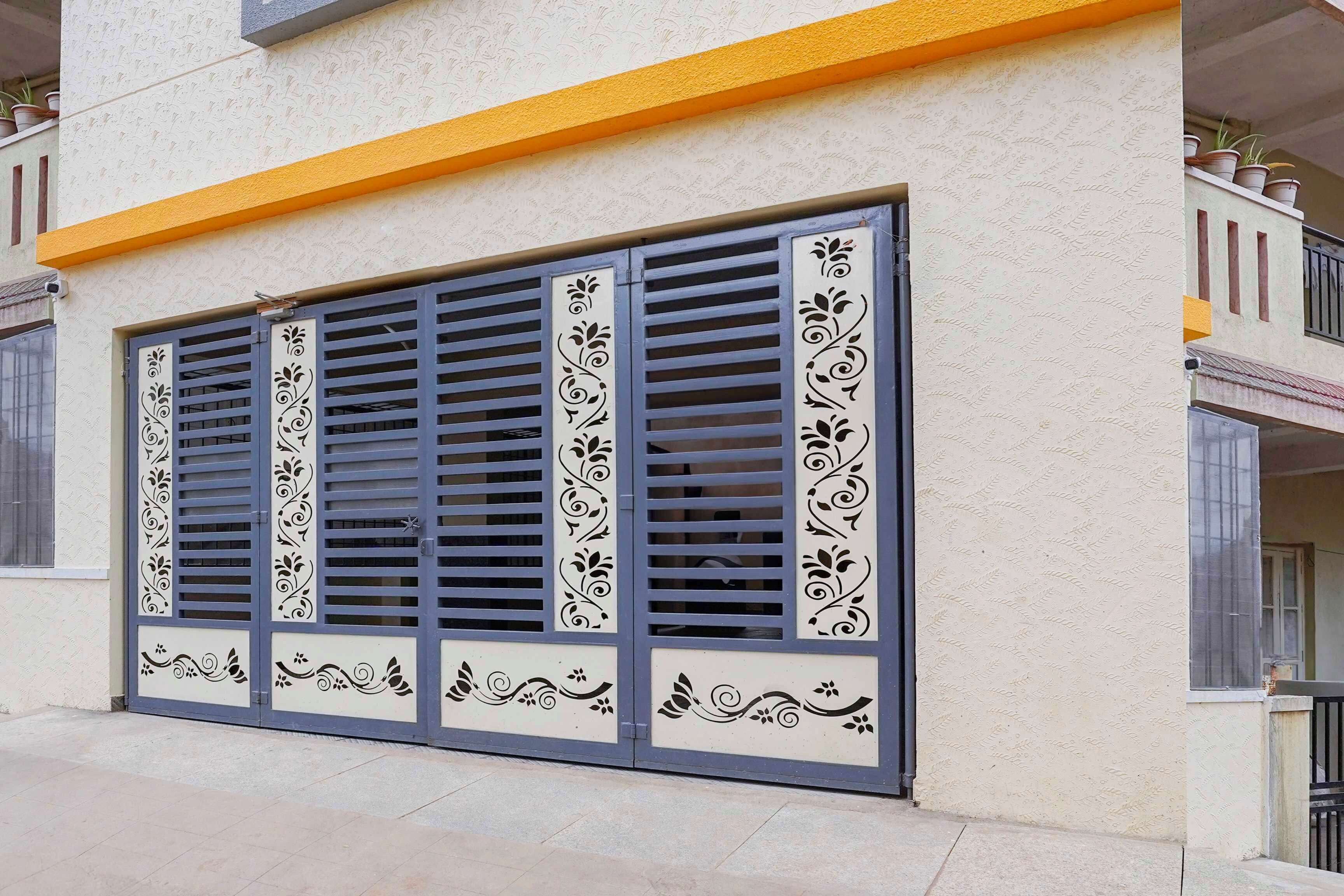 A building facade with a large window featuring decorative grills and a yellow upper section.