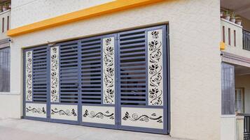 Eine Gebäudefassade mit einem großen Fenster, verziert mit schmiedeeisernen Gittern, und einem gelben oberen Abschnitt.
