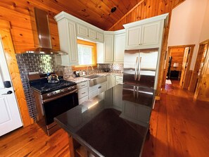 A modern kitchen with a stainless steel refrigerator, a gas stove, and white cabinetry. - Tree Top Retreat - Where Mountain Luxury Meets Adventure (Fleetwood)
