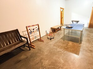 A room with a wooden bench, a table tennis table, and a wooden rack with balls. - Tree Top Retreat - Where Mountain Luxury Meets Adventure (Fleetwood)