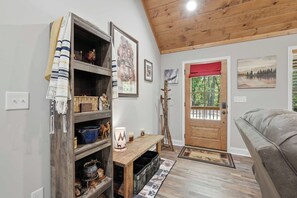 Ein gemütliches Interieur mit Holzbalkendecke, einer Sitzbank, einer Tür mit Aussicht und verschiedenen Dekorationselementen.