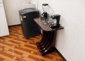 Eine Küchenzeile mit Mixer, Kaffeemaschine und Mülleimer.
