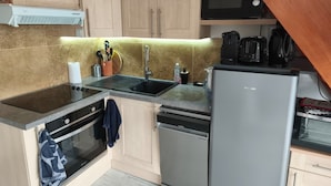 A compact kitchen with a microwave, stove, sink, and dishwasher. - Holiday Home 'Le Cottage Des Dunes - Erdeven' with Private Terrace, Garden and Wi-Fi (Erdeven)