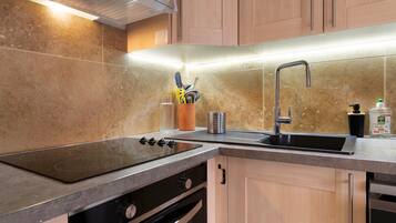 A kitchen with a stainless steel sink, a stove, and wooden cabinets.