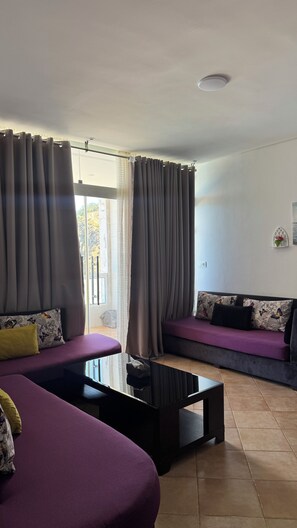 A modern living room with a sofa, a coffee table, and curtains.