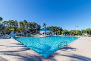 A swimming pool with a blue water feature, surrounded by lounge chairs and a covered seating area. - Key Lime Sunrise Top Floor Oceanfront 3404 (Tavernier)