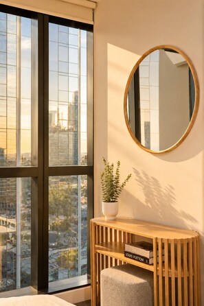 Een modern interieur met een groot raam, een ronde spiegel, een houten console en een potplant.