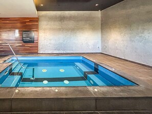 Ein rechteckiger, überdachter Pool mit einer Wand aus Holzpaneelen und einem Schild mit Sicherheitsanweisungen.