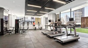Een moderne sportschool met loopbanden, krachttoestellen en uitzicht op de stad.