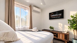 Ein Hotelzimmer mit Bett, Nachttisch, Pflanze und einem Schild an der Wand.