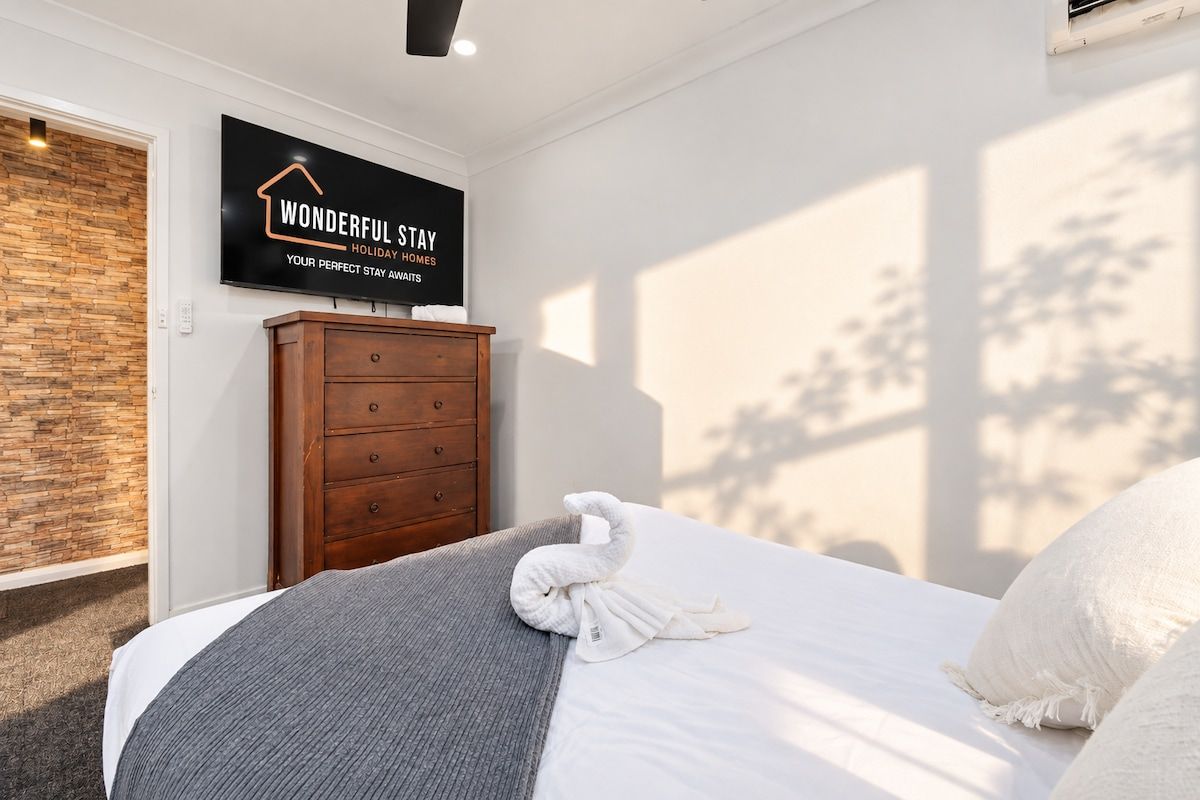 Ein Hotelzimmer mit einem Bett, einer Holzkommode, einem an der Wand befestigten Schild und einem Fenster mit Blick.