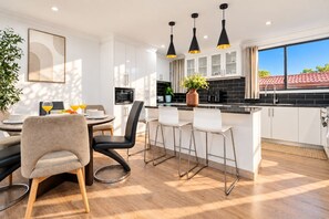 A modern kitchen with white cabinets, a black countertop, and pendant lighting.