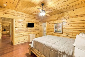 Ein Schlafzimmer einer Holzhütte mit einem Bett, einem Fernseher und einem Bild an der Wand.