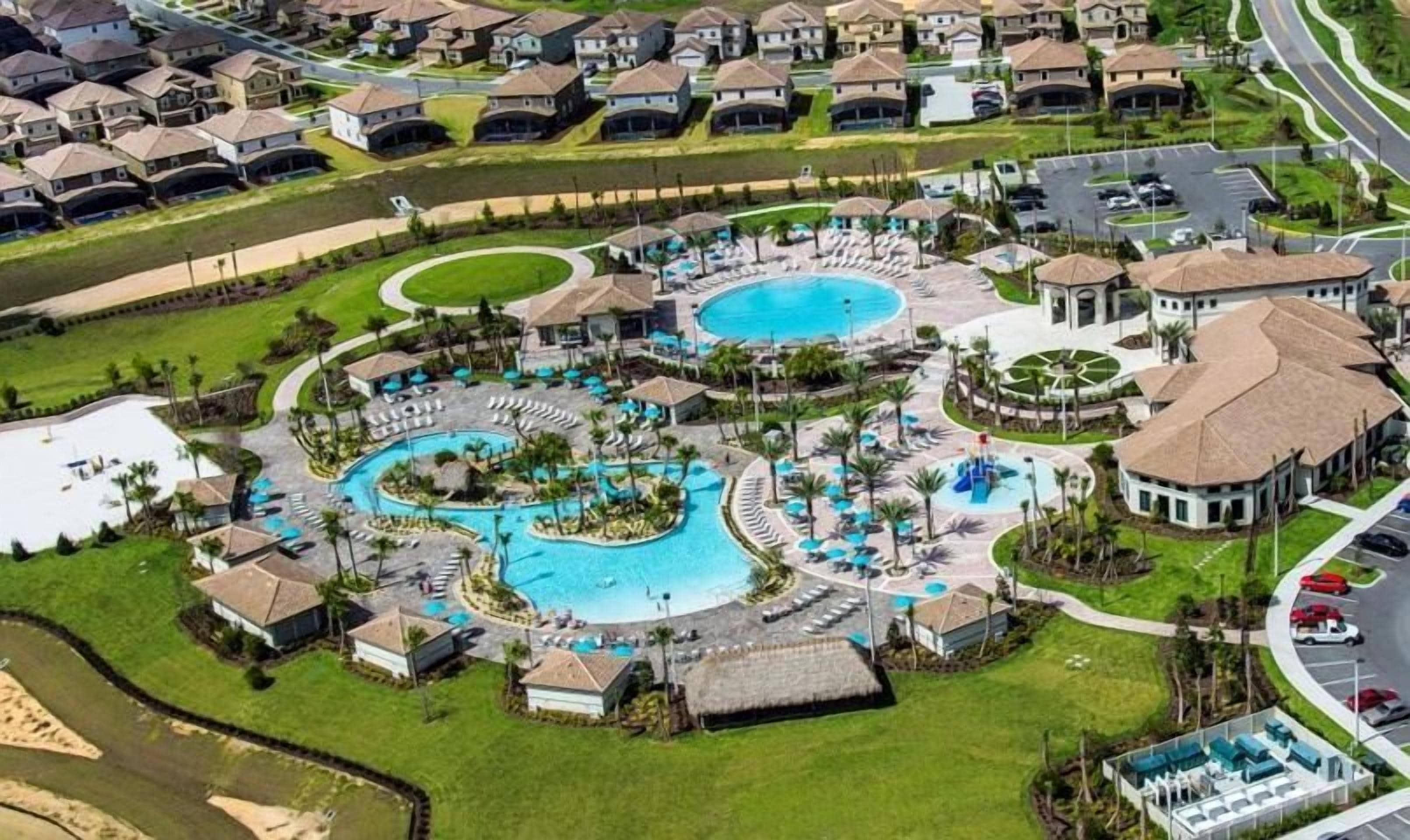 A resort with multiple swimming pools, a central water feature, and a parking area.