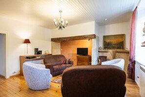 A cozy living room with a fireplace, a television, and a painting on the wall. - Lou Flaujer Cottage: Mountain View, Private Terrace & Wi-Fi in Pont-les-Bains (Salles-la-Source)