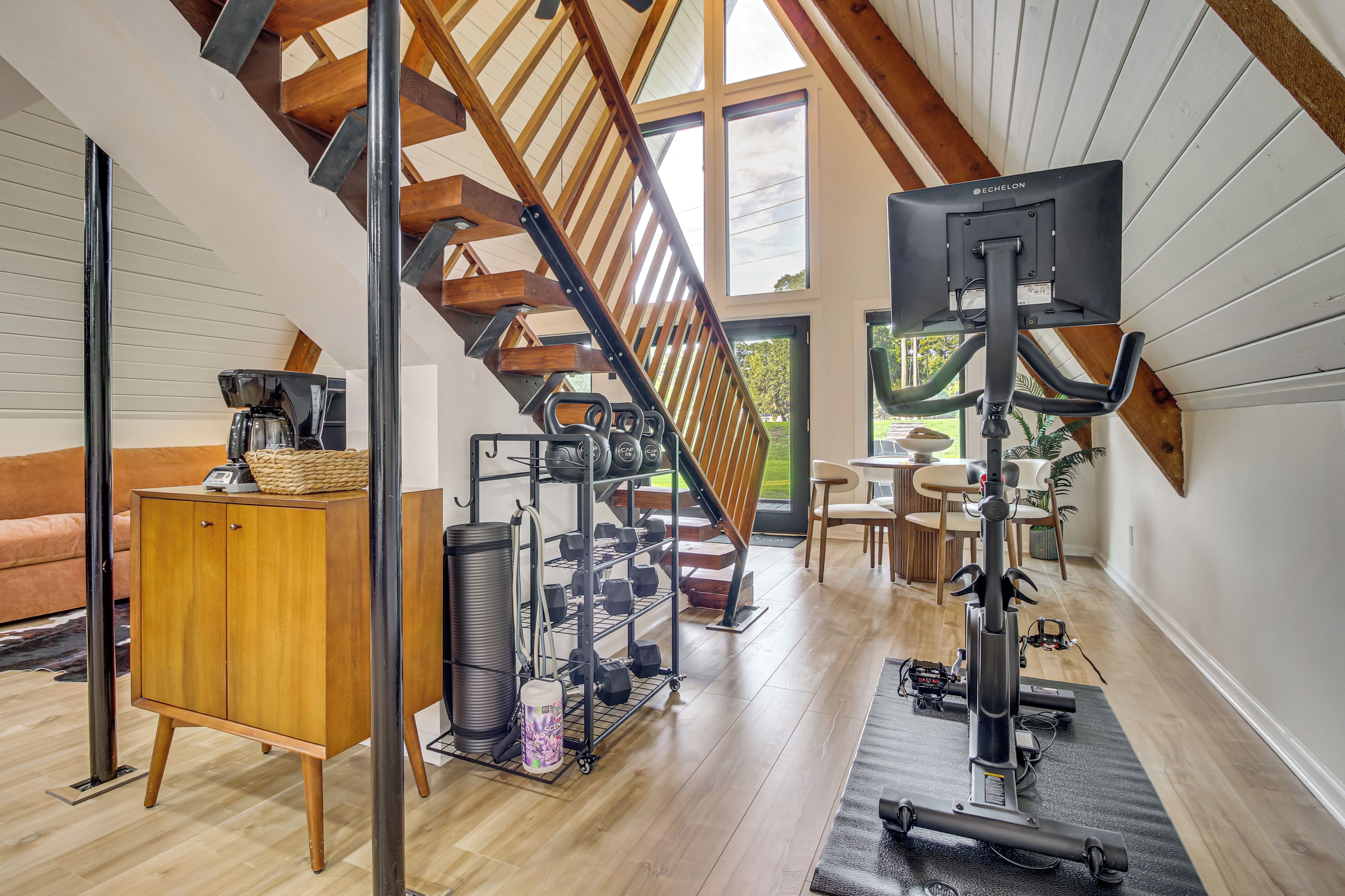Un gimnasio en casa con equipo de ejercicio, una escalera y un comedor.