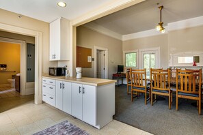 A spacious kitchen with white cabinetry, a dining area with wooden chairs, and a large island. - Walk to Decatur Square! Spacious Home w/ Porch (Decatur)