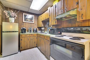 Una cocina con armarios de madera, un refrigerador, un microondas y una estufa.