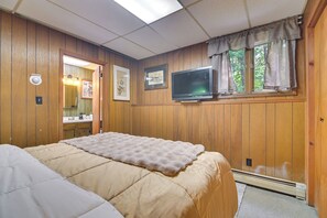 A room with a bed, a television, a window with curtains, and wooden walls. - Patio, Sunroom! Forest Retreat Near North Conway (Conway)