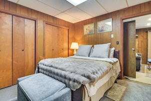Un dormitorio con una cama, una mesita de noche, una lámpara y un armario de madera.