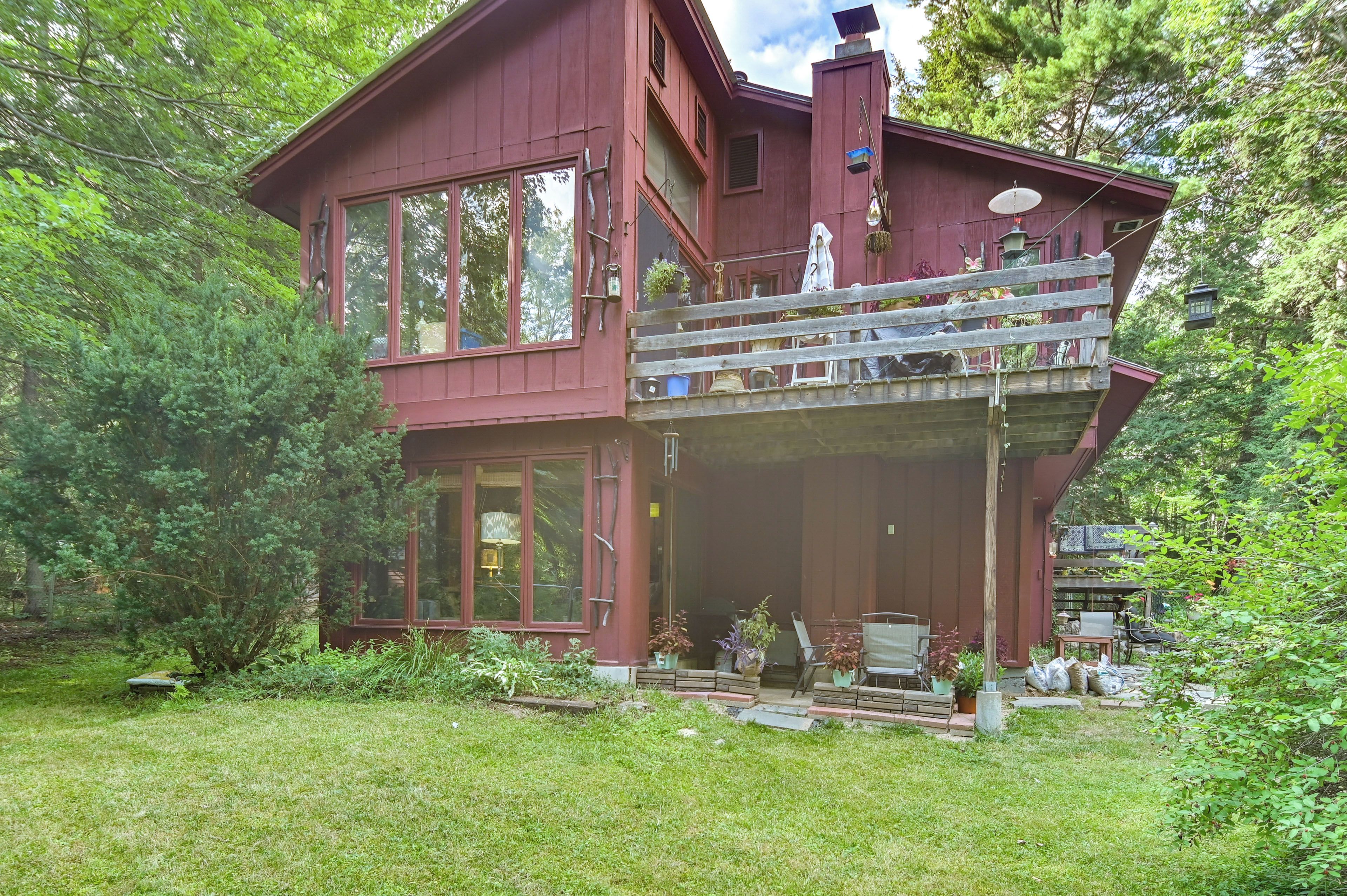 A two-story house with large windows, a balcony, and a garden area.