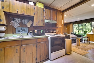 A kitchen with wooden cabinets, a stove, a microwave, and a sink.