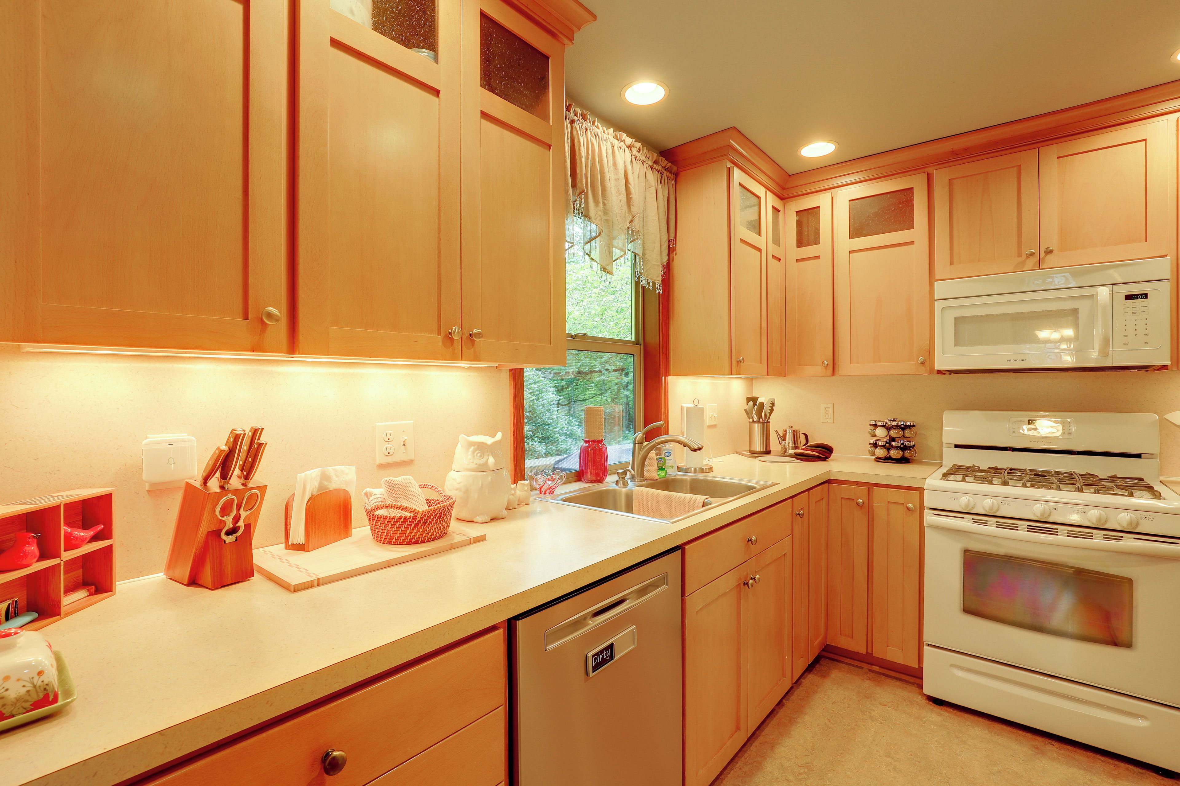 Una cocina con muebles de madera, microondas, estufa y lavavajillas.