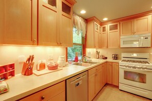 Una cocina con muebles de madera, microondas, estufa y lavavajillas.