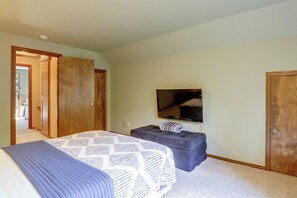 Un dormitorio con cama, televisor, armario y puerta que da a otra habitación.