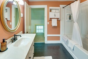 A bathroom with a double sink, a mirror, a shower with a curtain, and a towel rack.