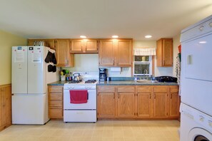 A kitchen with wooden cabinets, a white refrigerator, a stove, and a washing machine. - Fire Pit & Views! Lake Champlain Shoreline Stay (Plattsburgh)
