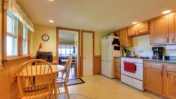 A kitchen with wooden cabinets, a stove, a refrigerator, and a dining table with chairs.