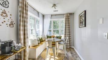 A cozy room with a wooden floor, a round table, and a bench with cushions.