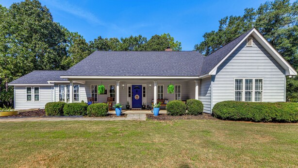 A two-story house with a front porch, a blue door, and a small garden. - Game Day Hideaway! Spacious Opelika Escape (Opelika)