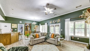 A spacious living room with a ceiling fan, a dining area, and a kitchen with a wooden countertop. - Game Day Hideaway! Spacious Opelika Escape (Opelika)