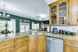 A kitchen with wooden cabinets, a built-in dishwasher, and a large island with a sink.